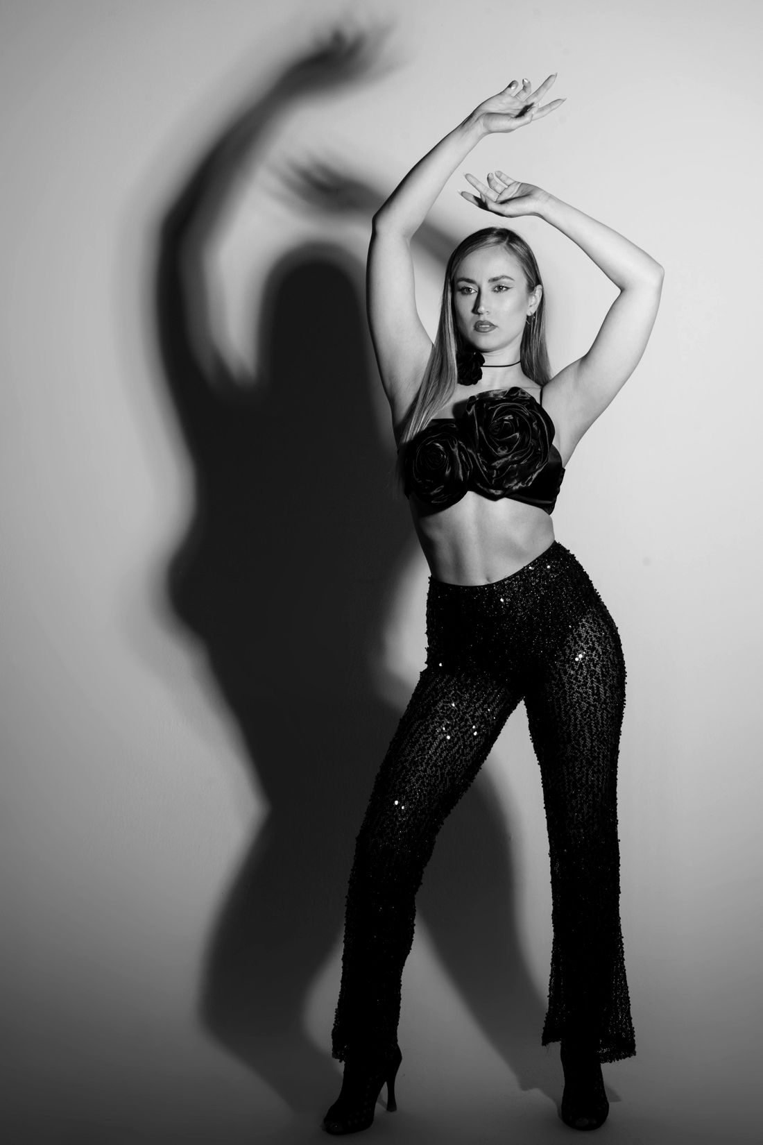 Estefanía Martínez con los brazos en alto en una pose de baile, con su sombra proyectada en la pared